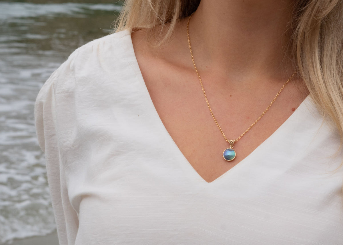Close-up of pāua shell jewellery showing iridescent blue and green colours from New Zealand abalone
