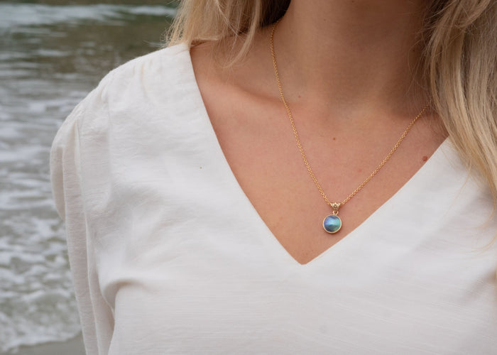Close-up of pāua shell jewellery showing iridescent blue and green colours from New Zealand abalone