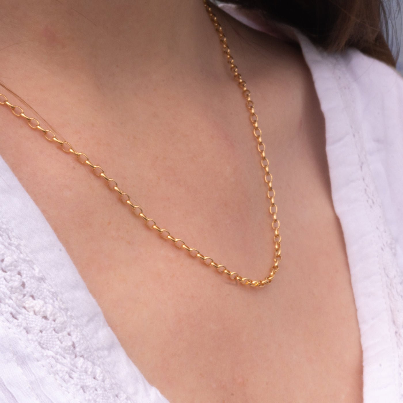 Gold necklace on a person with a blurred beach background